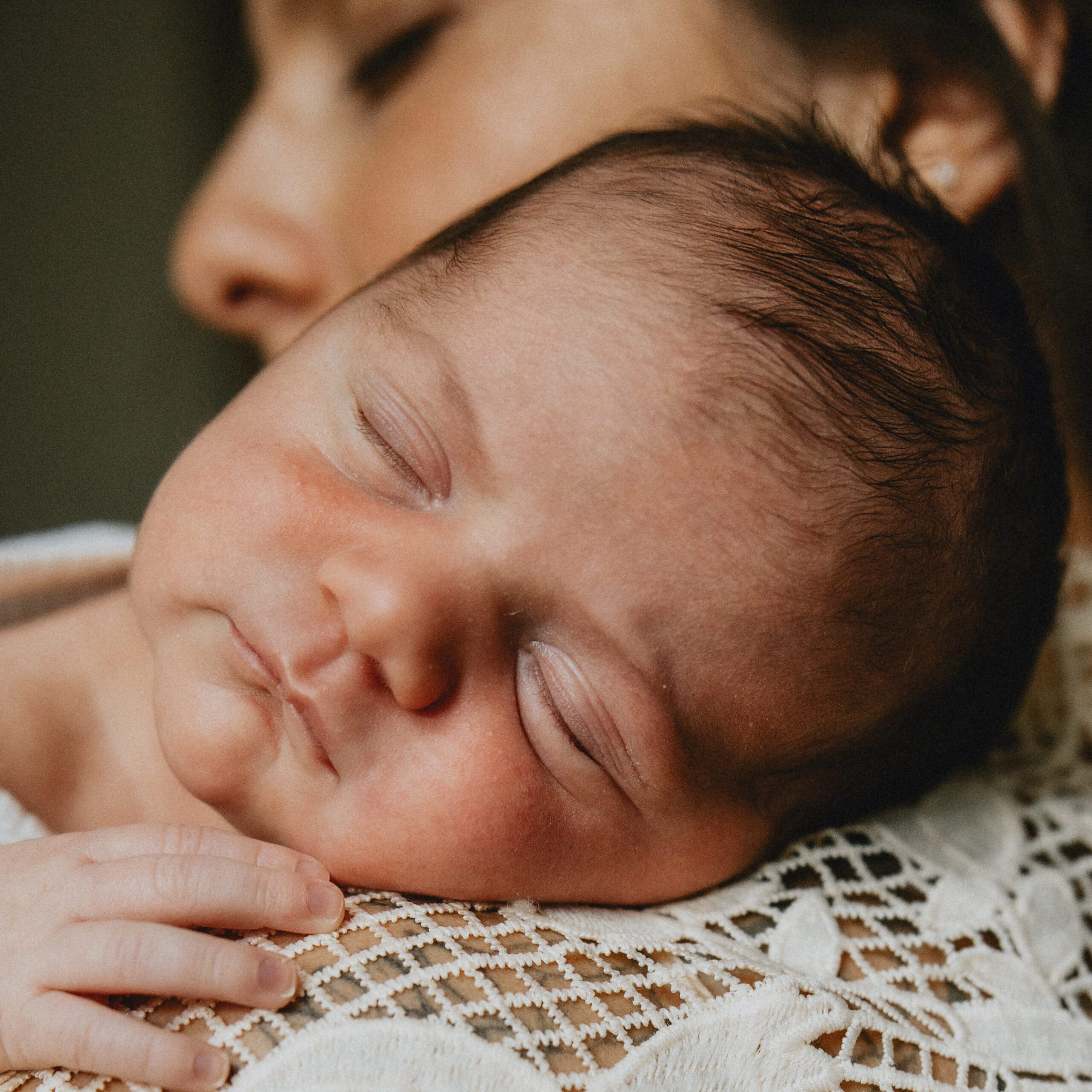 in-home newborn photo of baby girl sleeping on mother's shoulder