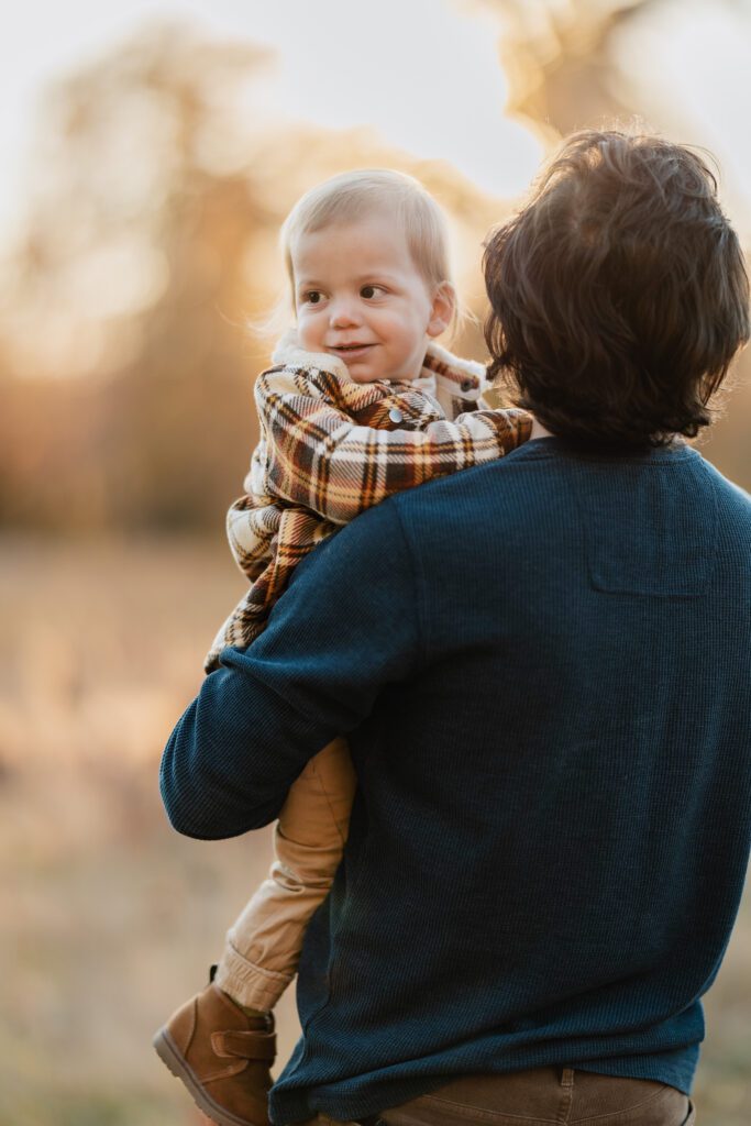 Fall family photo of toddler boy over father's shoulder
