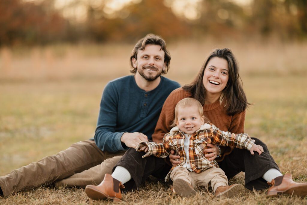 Family sitting in field wearing Fall sweaters and boots