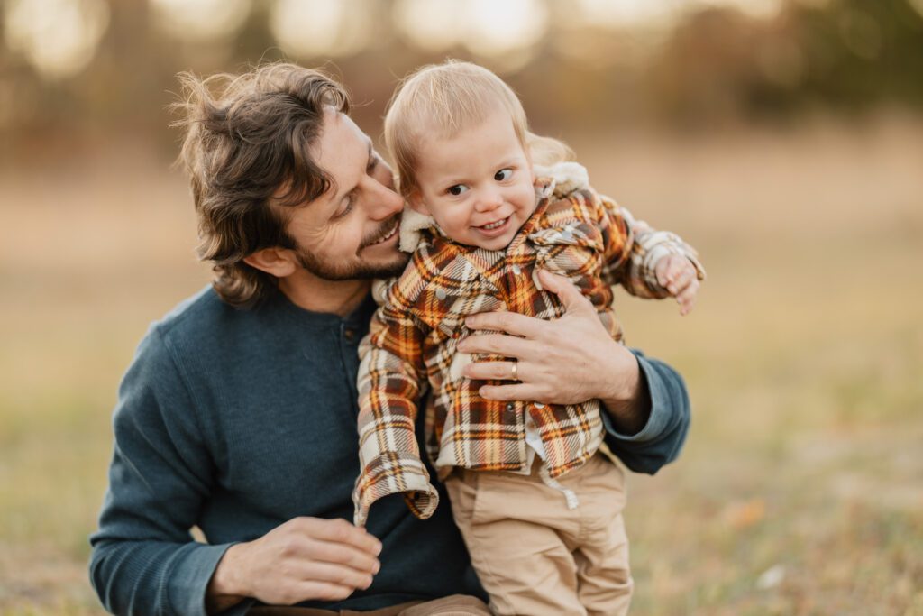 Fall family photo of Dad playing with toddler son