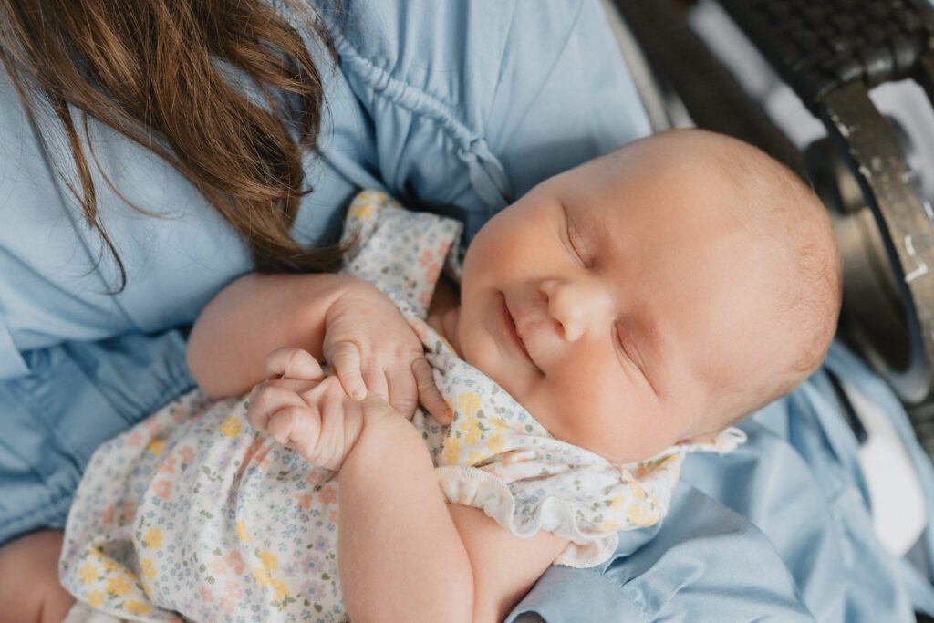 Newborn baby girl smiling while sleeping in her mother's arms